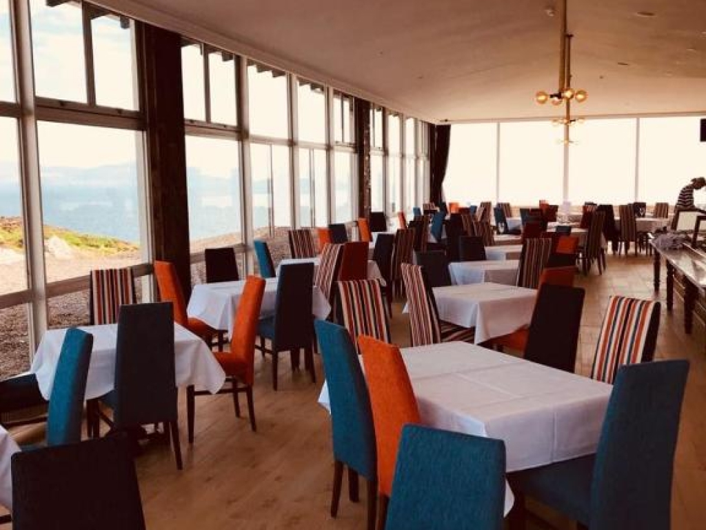 Set tables and floor-to-ceiling windows overlooking the Atlantic Ocean and Beara mountains in the Derrynane Coast Hotel restaurant.