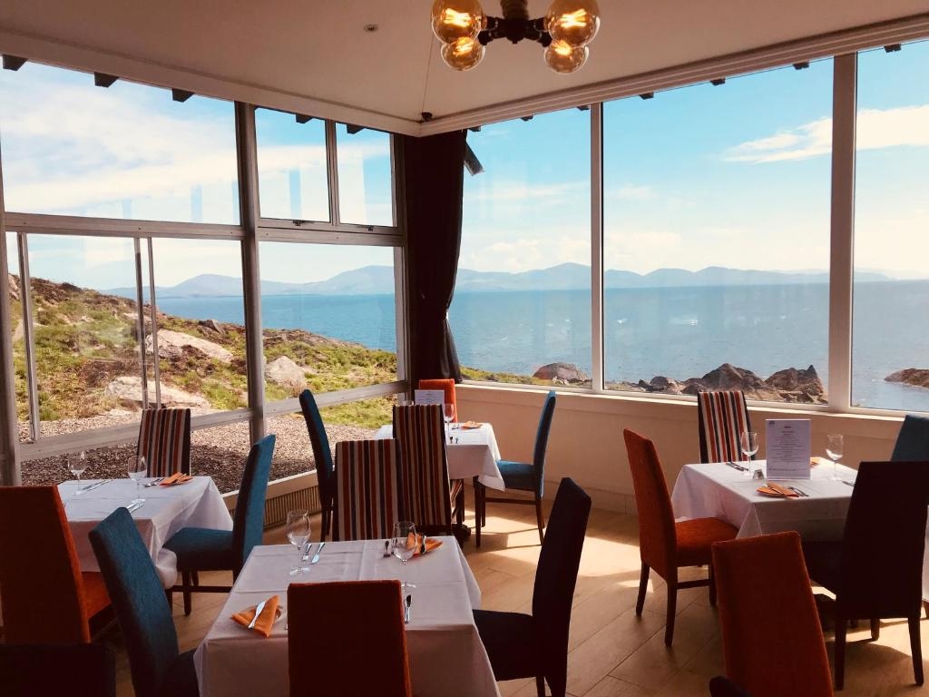 Set restaurant tables in front of huge windows looking across Kenmare Bay to the Beara Peninsula at the Derrynane Coast Hotel.