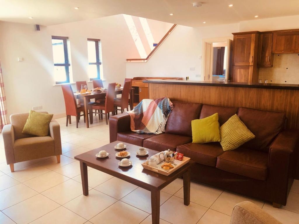 Open-plan kitchen, dining and lounge in a Derrynane Coast Hotel self-catering holiday home, with leather sofa and breakfast tray.